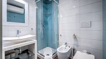 Un baño moderno con ducha envuelta en vidrio, lavamanos blanco y bidé.