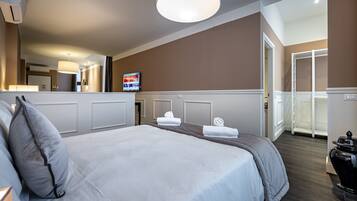 A hotel room with a large bed, a television, and a bathroom with a shower and toilet.