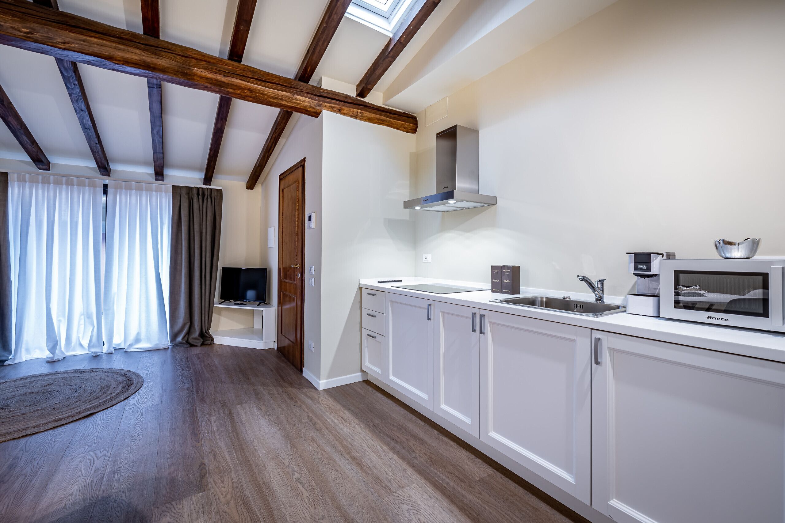 A modern kitchen with white cabinets, a stainless steel sink, and a built-in microwave.