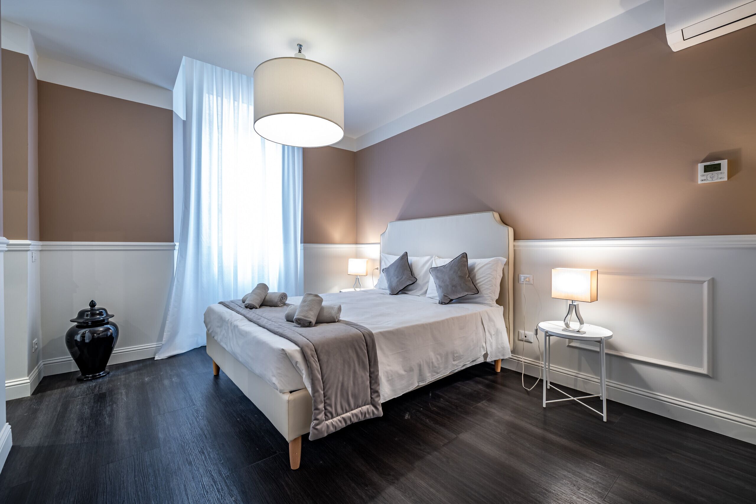 Une chambre à coucher avec un lit, des lampes de chevet, une table de chevet et une fenêtre avec des rideaux.