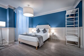 Et moderne soveværelse med seng, sengeborde med lamper, en hængende lampe og en hvid metalkasse.