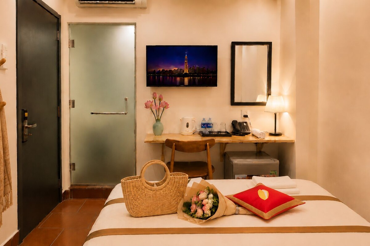 Une chambre d’hôtel comprenant un lit, un bureau avec une chaise, une télévision, un miroir et une fenêtre donnant sur le paysage urbain.