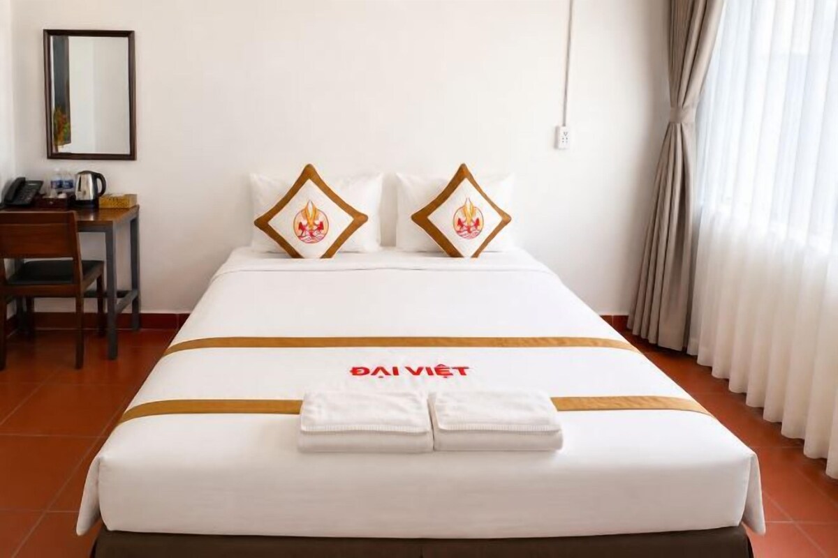 Une chambre d’hôtel avec un lit, un bureau et une chaise.