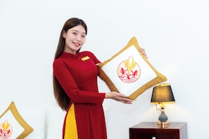 A person in a red dress holding a framed item with a red and yellow emblem.