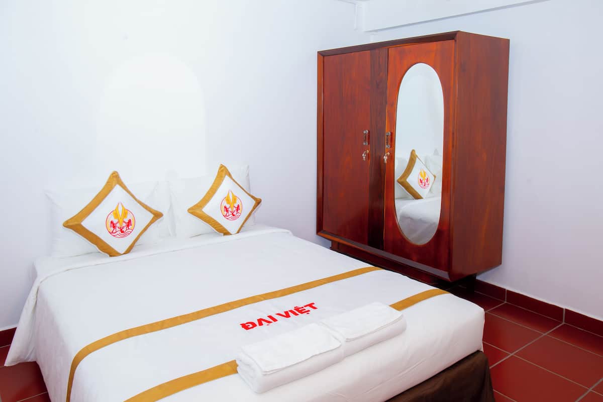 A hotel room with a bed, a wardrobe, and a mirror.