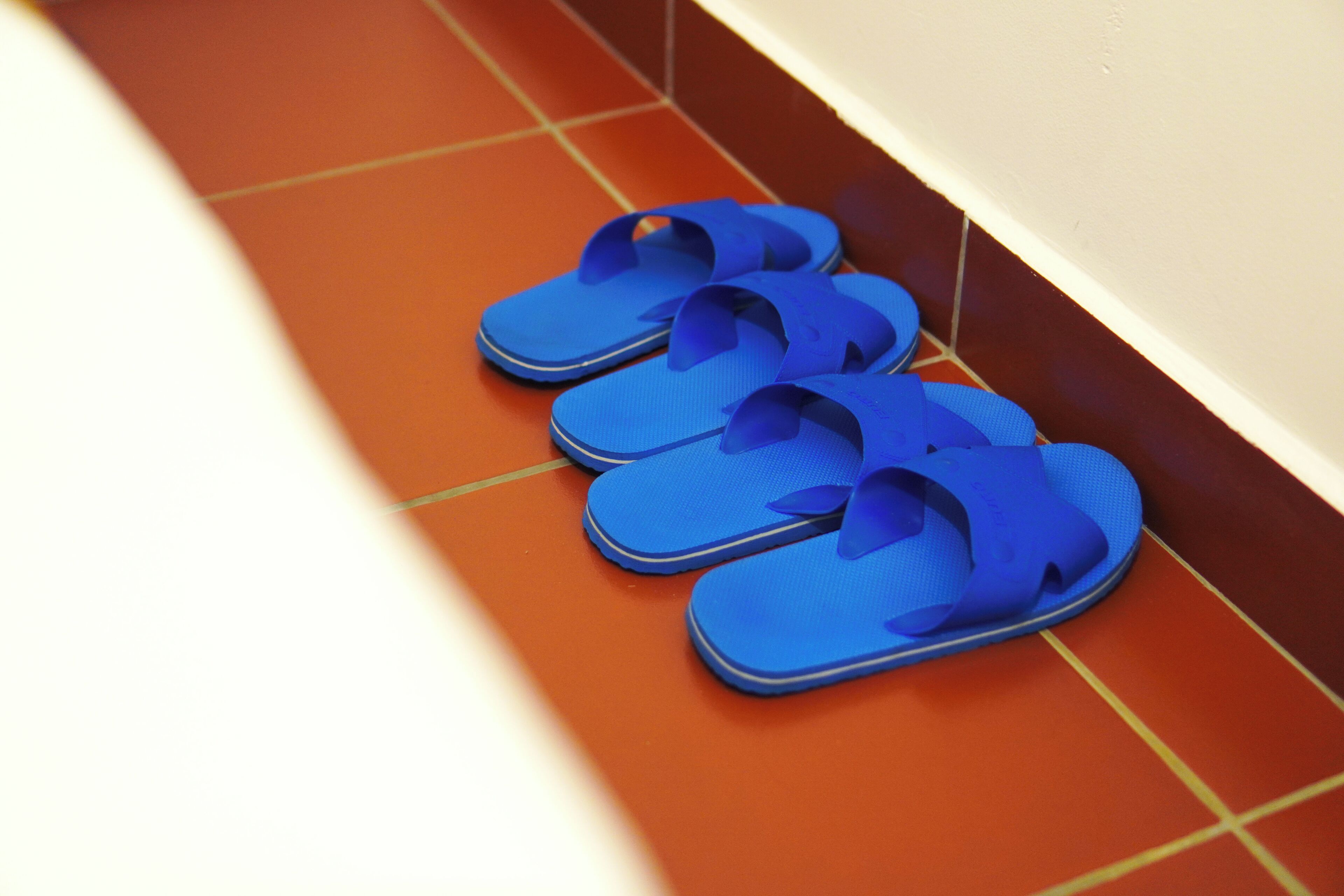 A pair of blue flip-flops on a tiled floor.