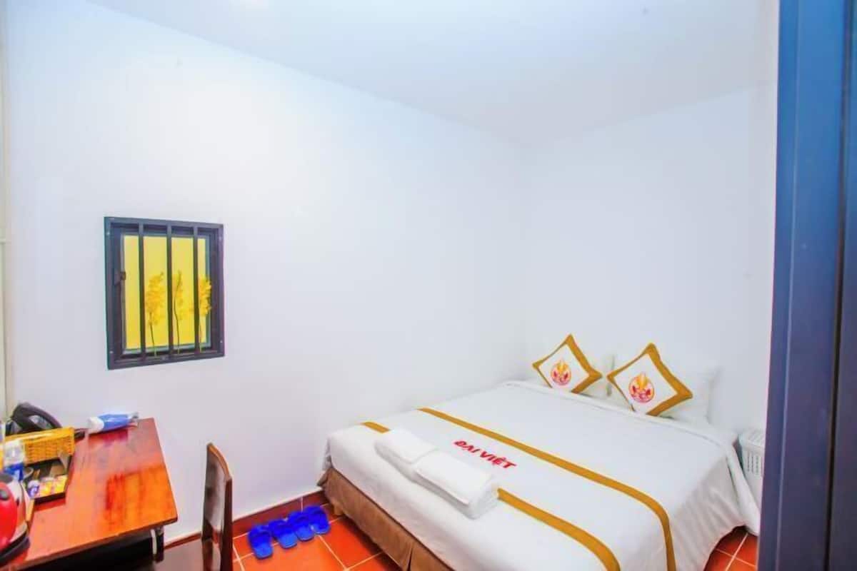 A hotel room with a bed, a desk, and a chair.