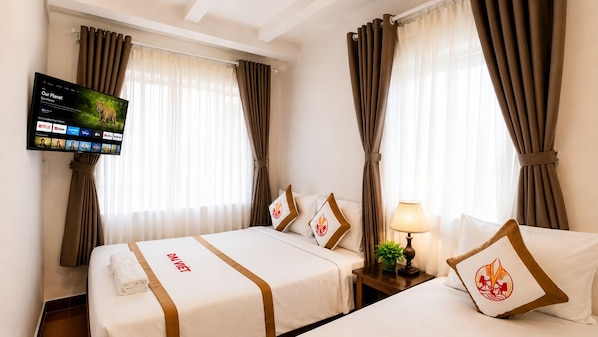 A hotel room with two beds, a TV mounted on the wall, and curtains on the windows. - The Rice Hotel & Tour - 191 Bui Vien (Ho Chi Minh City)