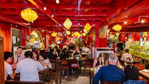 Um restaurante movimentado com mobiliário de madeira e decoração vermelha.
