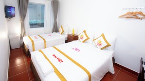 A hotel room with two beds, each with a white bedspread and a golden stripe, a small wooden nightstand, a television mounted on the wall, and a window with curtains. - The Rice Hotel & Tour - 191 Bui Vien (Ho Chi Minh City)