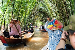 A narrow waterway with boats, surrounded by dense foliage. - The Rice Hotel & Tour - 191 Bui Vien (Ho Chi Minh City)