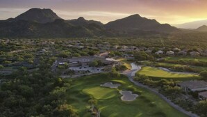 Vista aérea de un campo de golf con múltiples zonas verdes, búnkeres de arena y un club de campo.