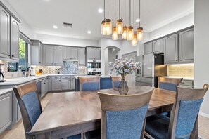Een moderne keuken met grijze kasten, een houten eettafel en blauwe fauteuils.