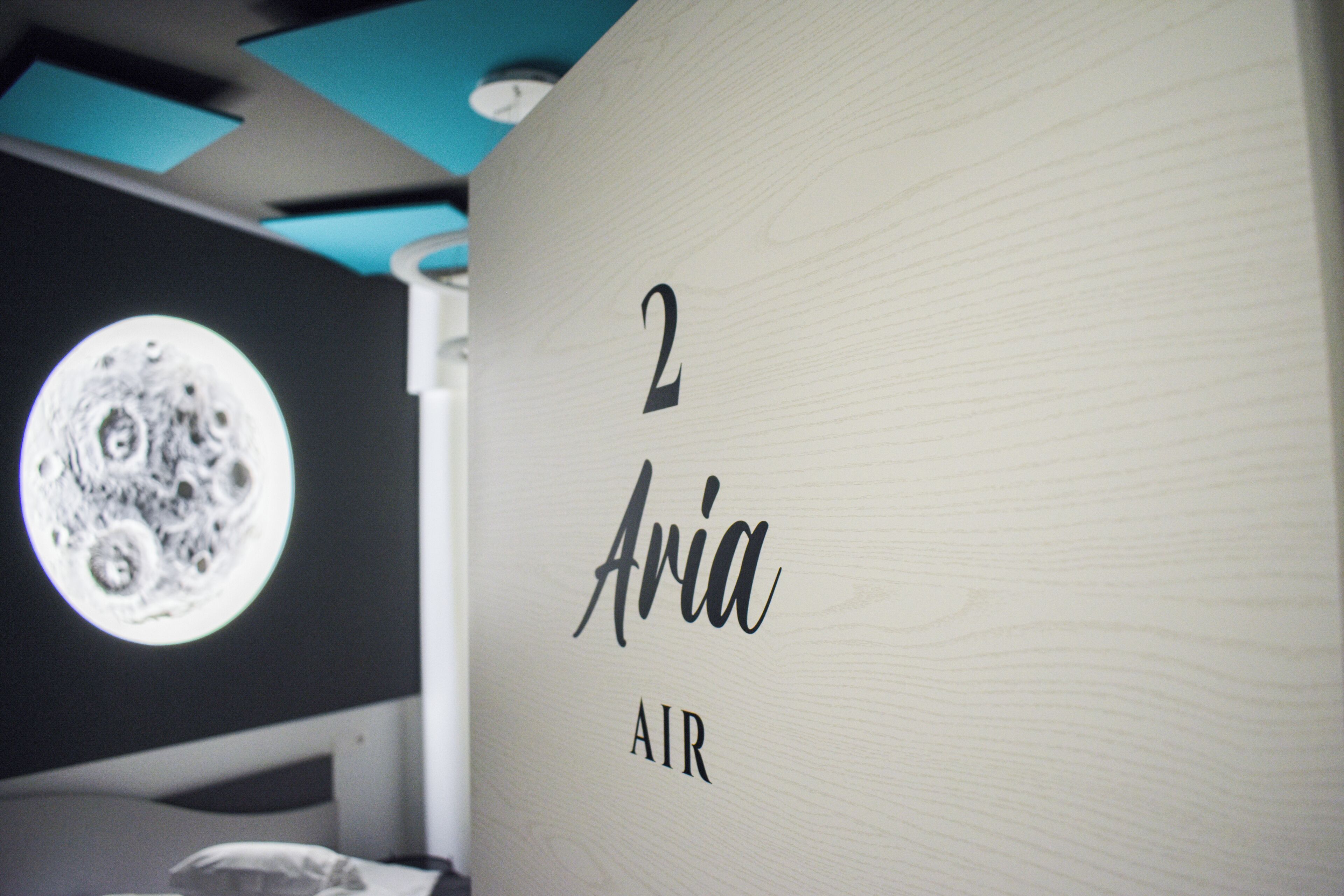 Een kamer met een houten wand waarop het getal '2' en de naam 'Aria' staan, met het woord 'AIR' eronder.