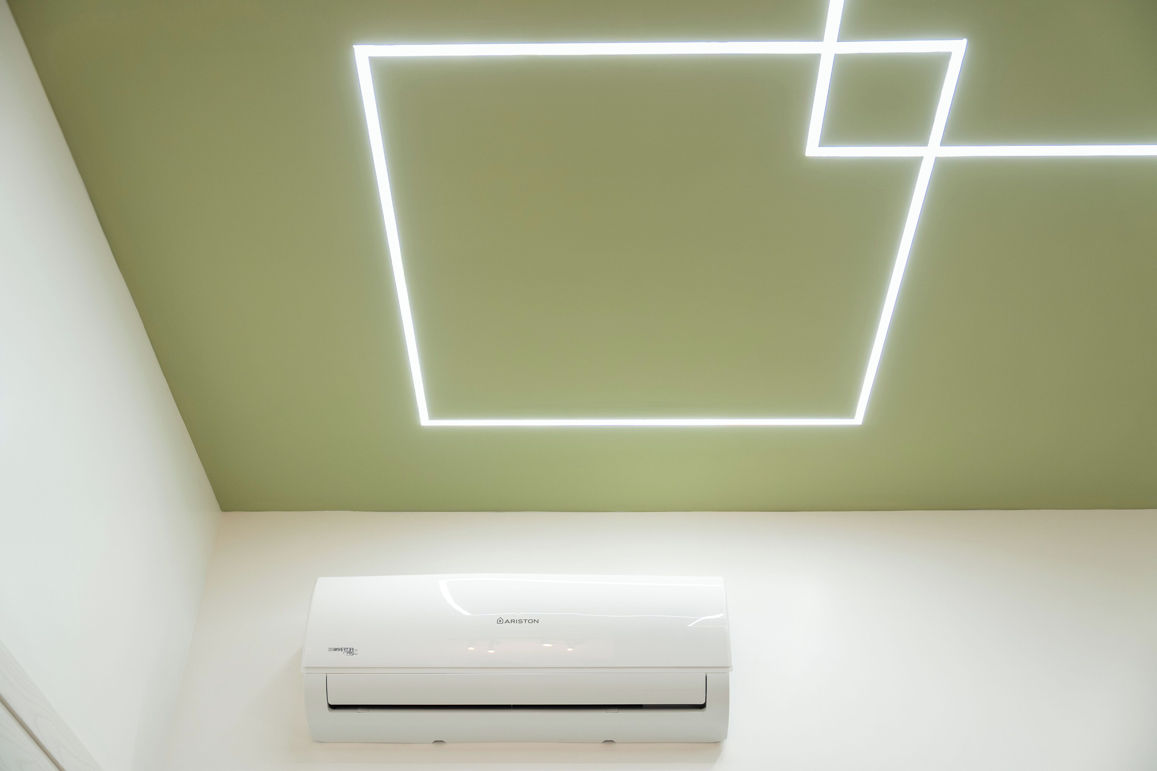 Techo con una lámpara de diseño geométrico y una unidad de aire acondicionado blanca debajo.