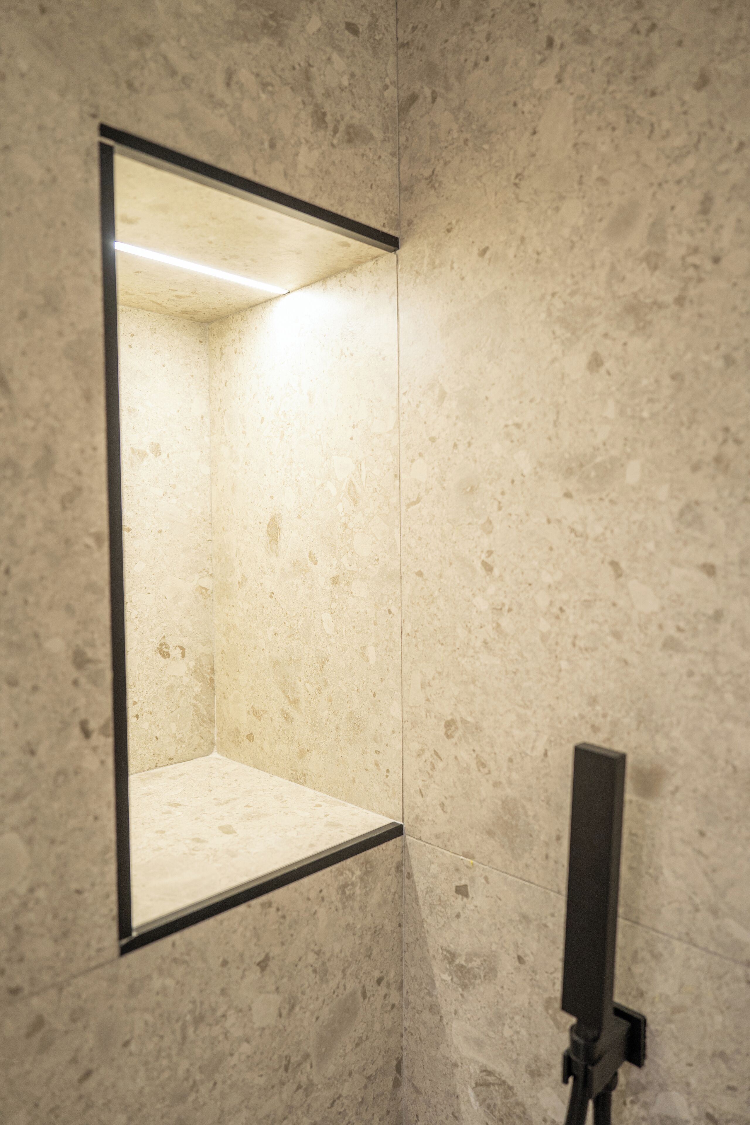 A bathroom with a large mirror, a light fixture above it, and a marble wall.