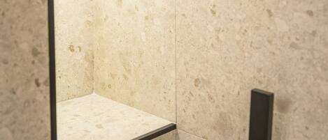 A bathroom with a large mirror, a light fixture above it, and a marble wall.