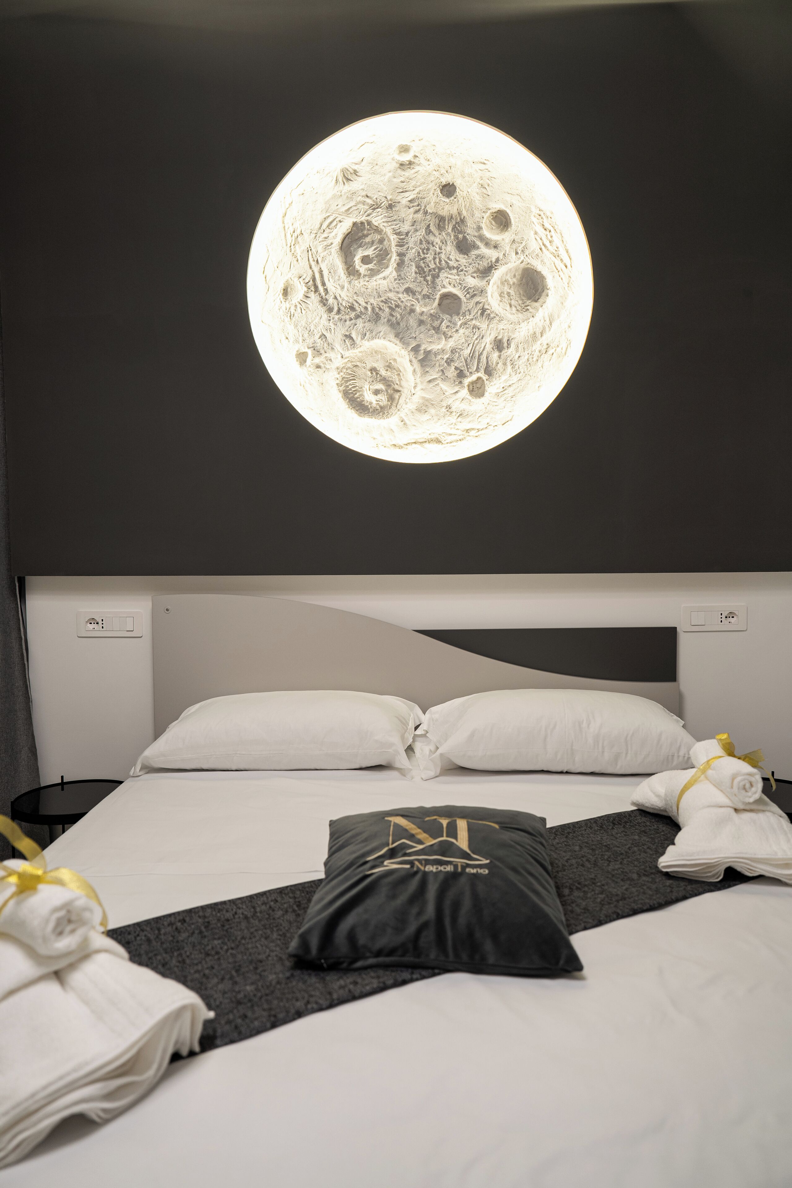 Ein Hotelzimmer mit Bett, Kissen, Decke und einer runden Wandleuchte.