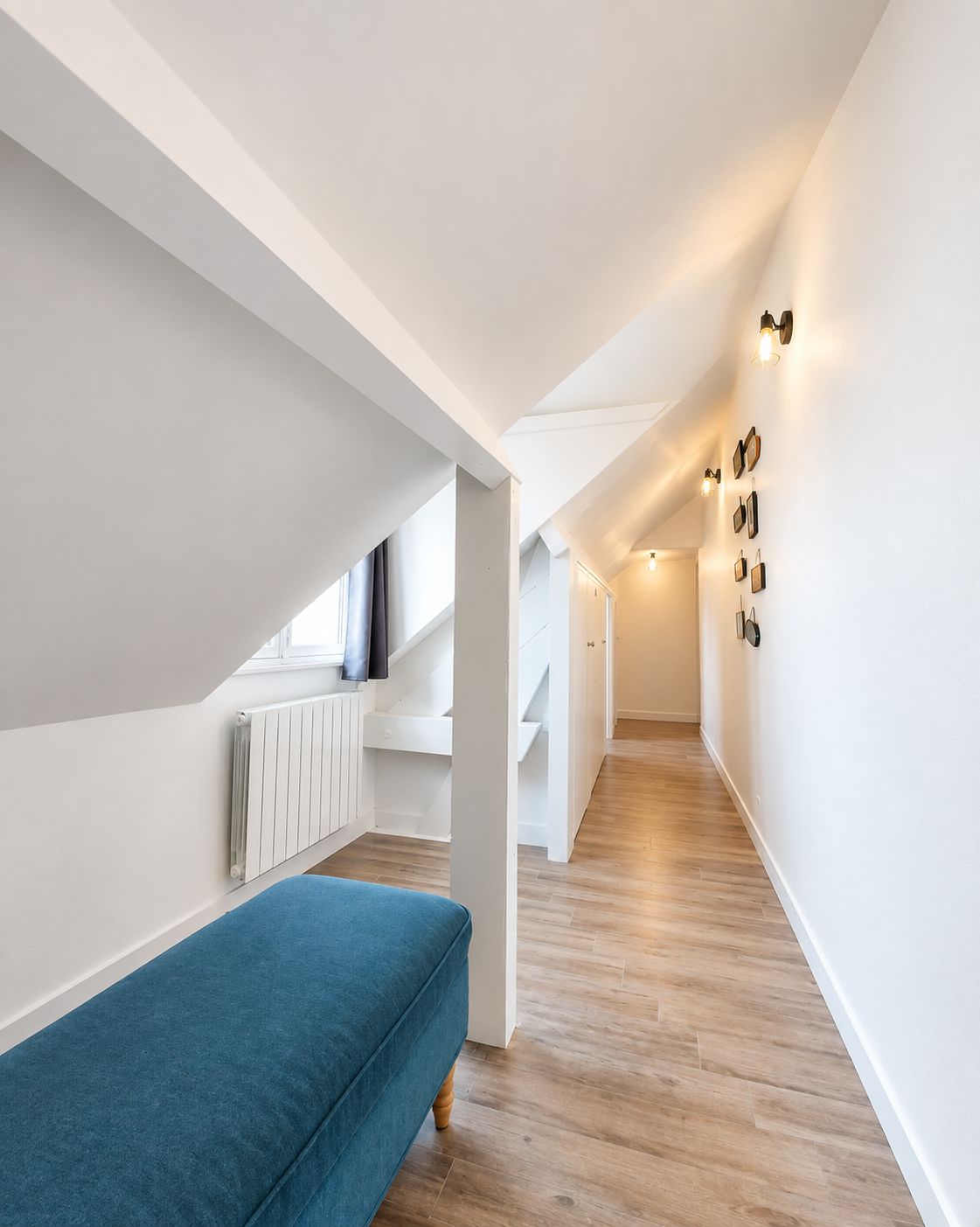 Een modern interieur met een houten vloer, witte wanden en een blauwe bank.