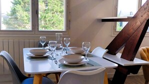 A dining area with a table set for four, surrounded by chairs with wooden legs and cushioned seats. - Charming seaside apartment (Dinard)