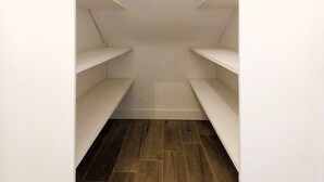 A narrow walk-in closet with white shelving and a wooden floor. - Charming seaside apartment (Dinard)