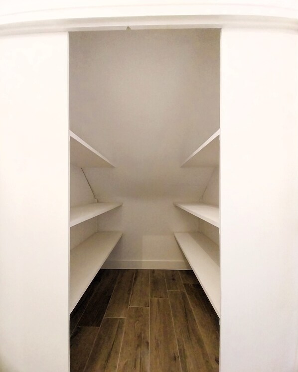 A narrow walk-in closet with white shelving and a wooden floor. - Charming seaside apartment (Dinard)