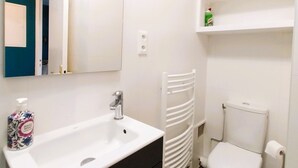 A modern bathroom with a white sink, a mirror, a towel rack, and a toilet. - Charming seaside apartment (Dinard)