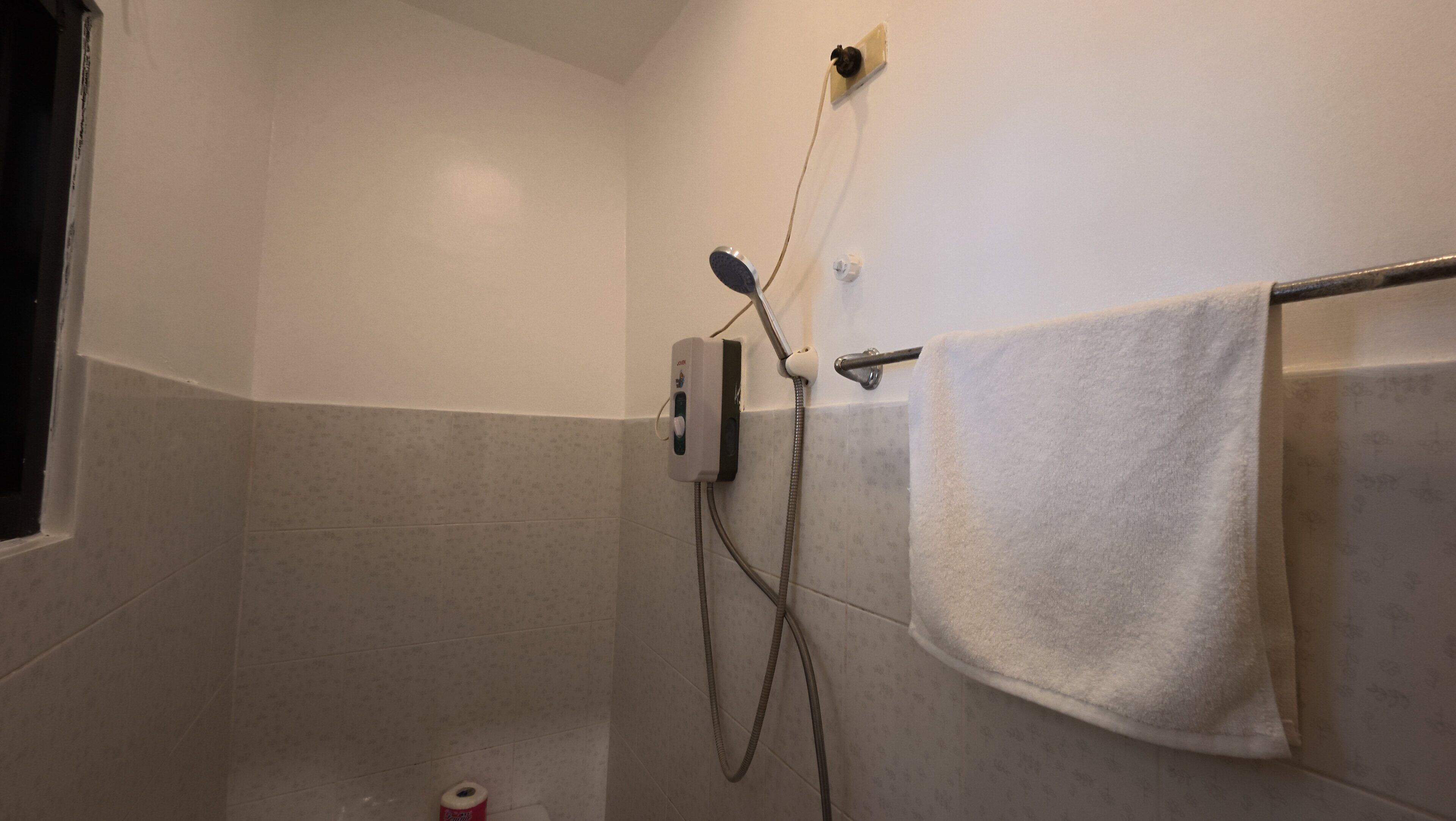 A small, tiled shower room with a towel rack and a handheld showerhead.