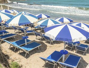 A beach with rows of blue and white striped umbrellas and matching lounge chairs. - Hotiday Cefalù Mazzaforno (Cefalù)