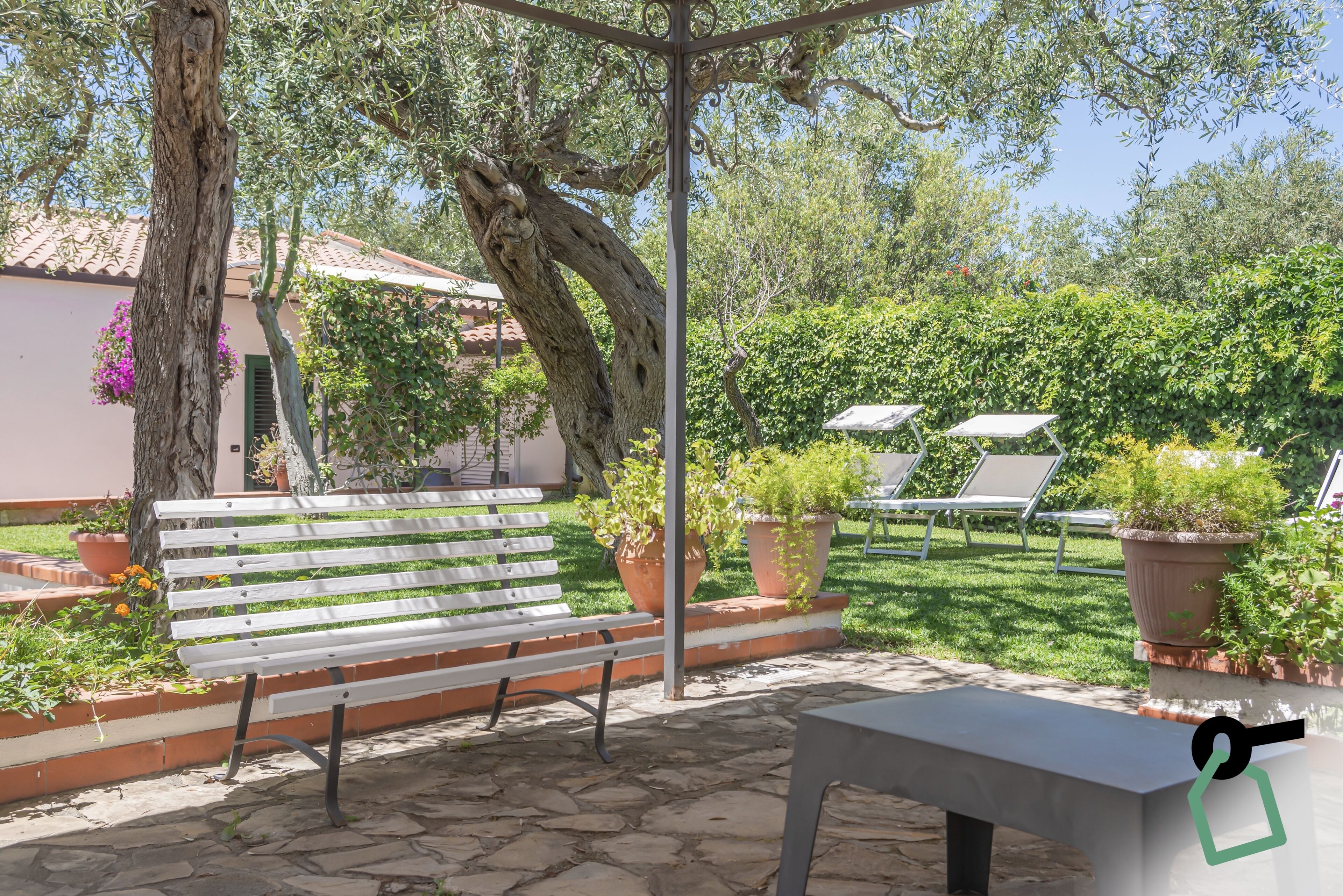 Une terrasse extérieure avec un banc blanc, une table et des plantes en pot.