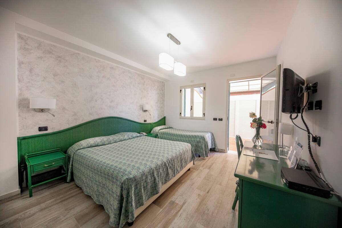 Ein Schlafzimmer mit zwei Betten, einem Schreibtisch, einem Spiegel und einem Fernseher.