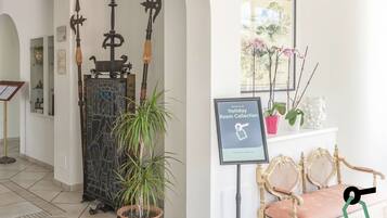 A reception area with a decorative gate, potted plants, a framed welcome sign, and a bench.