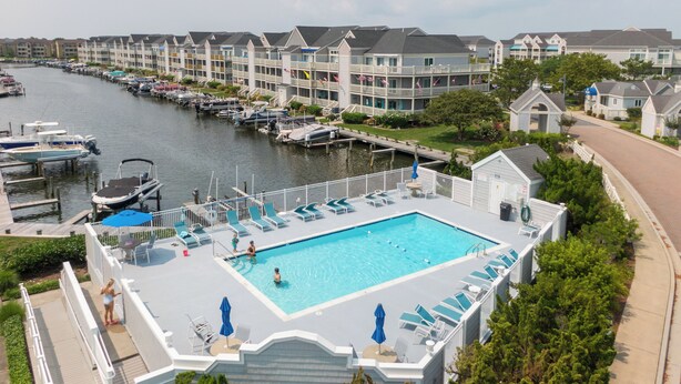 A swimming pool with lounge chairs and a docked boat area.