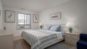 A bedroom with a bed, bedside tables, a window, and wall art.