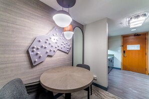 A conference room with a round table, gray chairs, a wall-mounted light fixture, and a wooden door in the background. - Updated Pet Friendly Monache Studio with Views! (Mammoth Lakes)