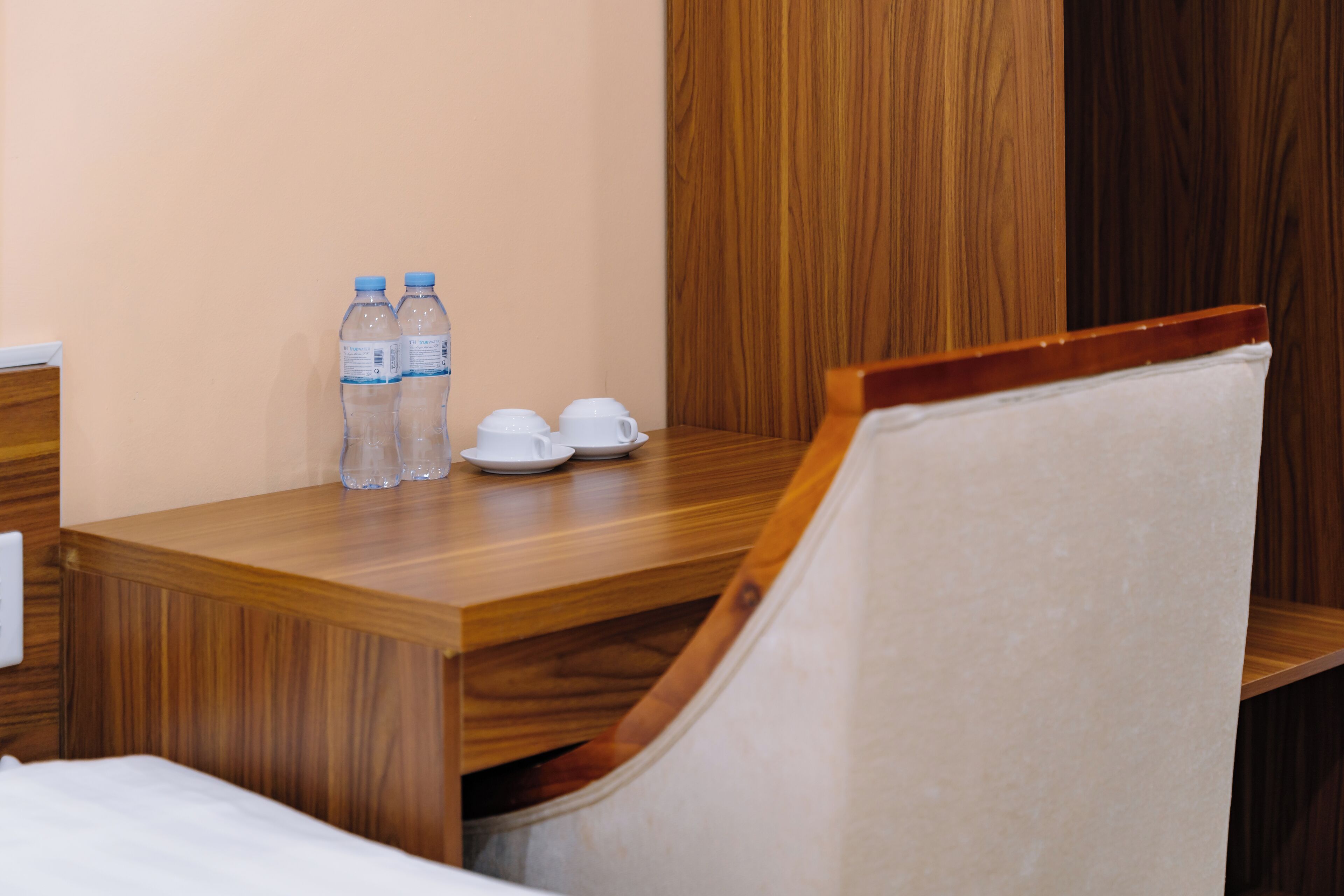 A wooden desk with two water bottles, two white cups, and a plate.