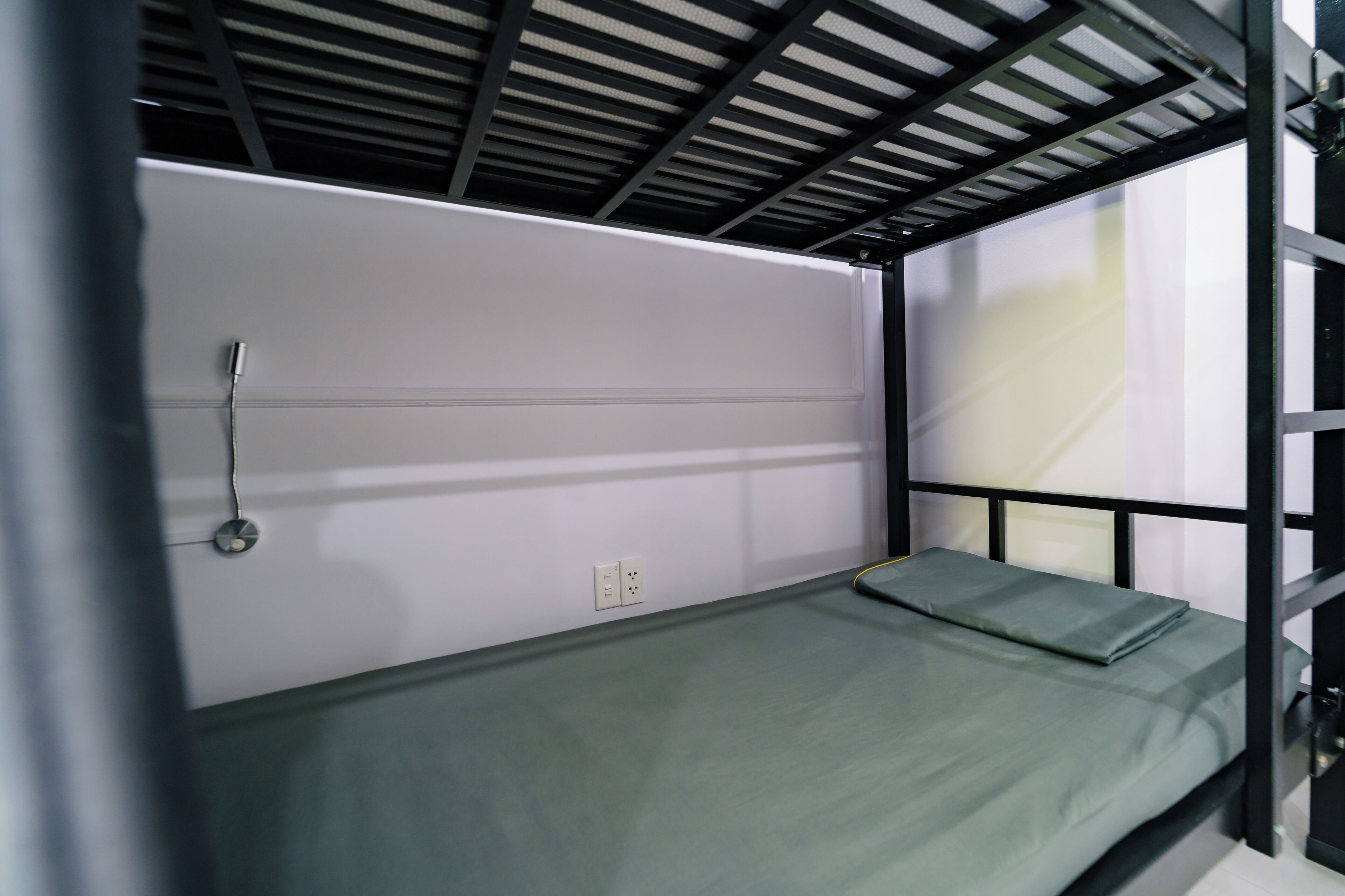 Un lit superposé avec un matelas vert et une structure en métal.