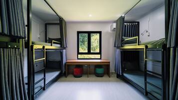 Ein Schlafsaalzimmer mit Etagenbetten, einem Schreibtisch und einem Fenster.