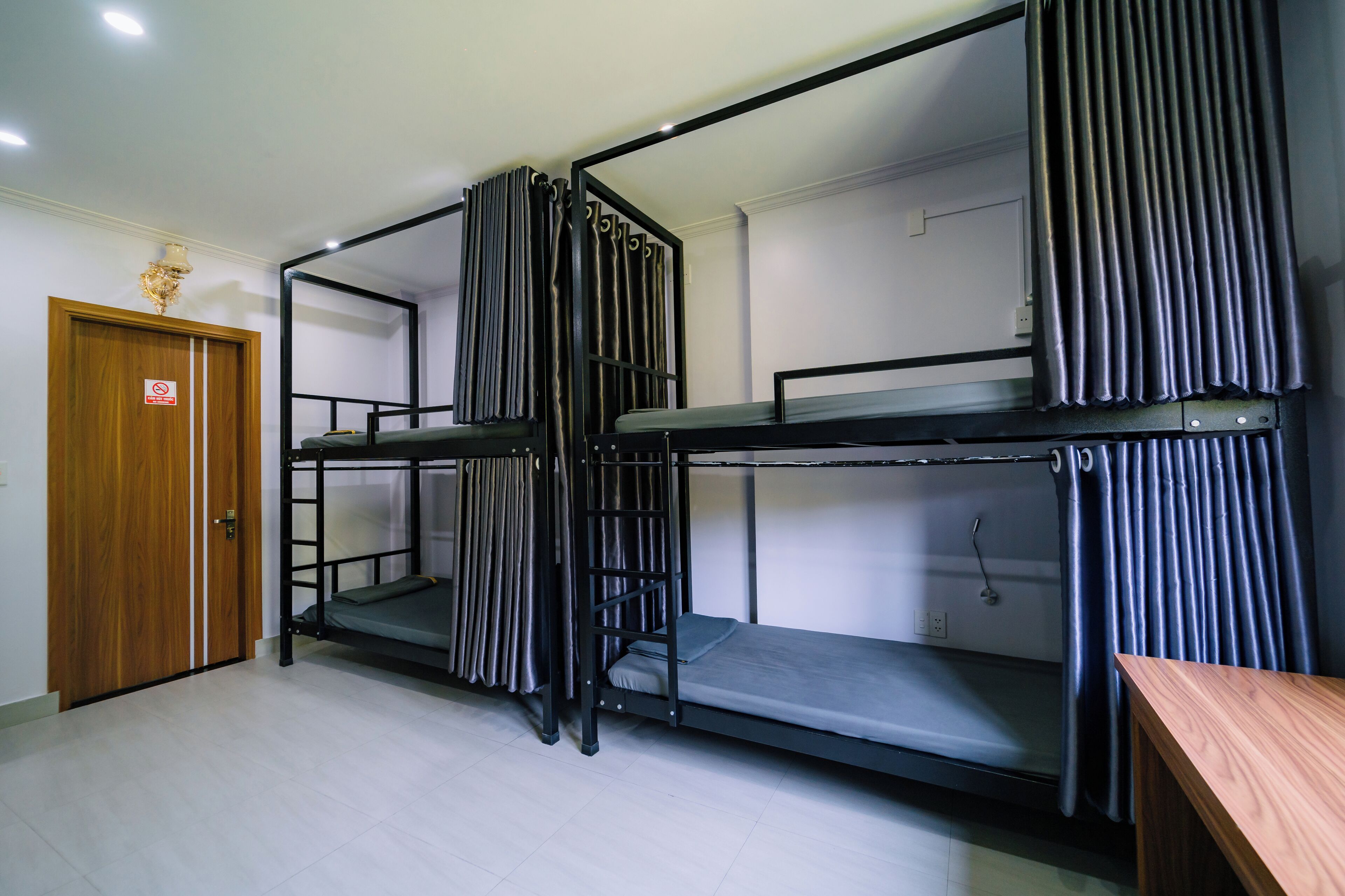 A room with bunk beds, a wooden door, and a small table.