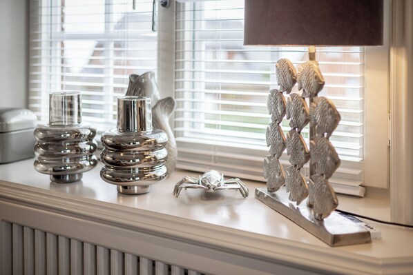 A window with decorative metal fish sculptures and a small metal crab on a white radiator. - 3-room apartment on the top floor/first floor, approximately 57 m², in Munkmarsch (Sylt / OT Munkmarsch)