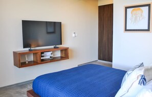 A bedroom with a large bed, a TV mounted on a wooden shelf, and a framed picture on the wall. - Celestial Penthouse with Private Jacuzzi (Tulum)