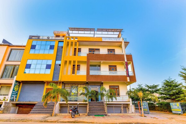 A multi-story hotel with a yellow facade, balconies, and a visible entrance with steps. - Hotel Kalyan and Banquets (Jaipur)