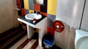 Un bagno con parete rivestita di piastrelle a scacchi, un lavandino, un water e una doccia.