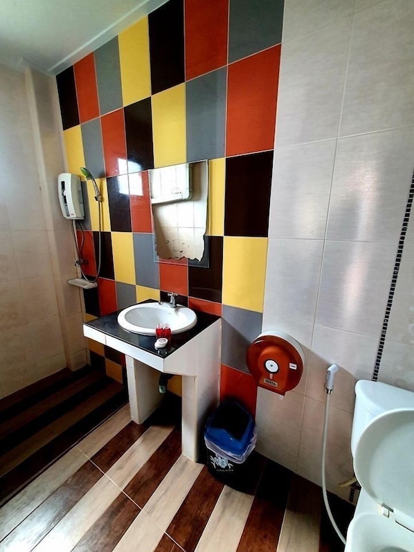 A bathroom with a checkered tile wall, a sink, a toilet, and a shower. - Virawan pool resort kohlarn (Koh Lan)