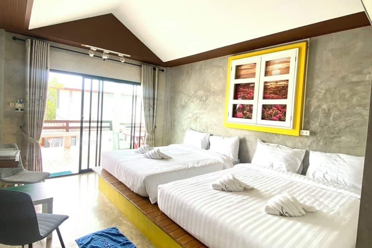 A hotel room with two beds, a desk, and a large window.