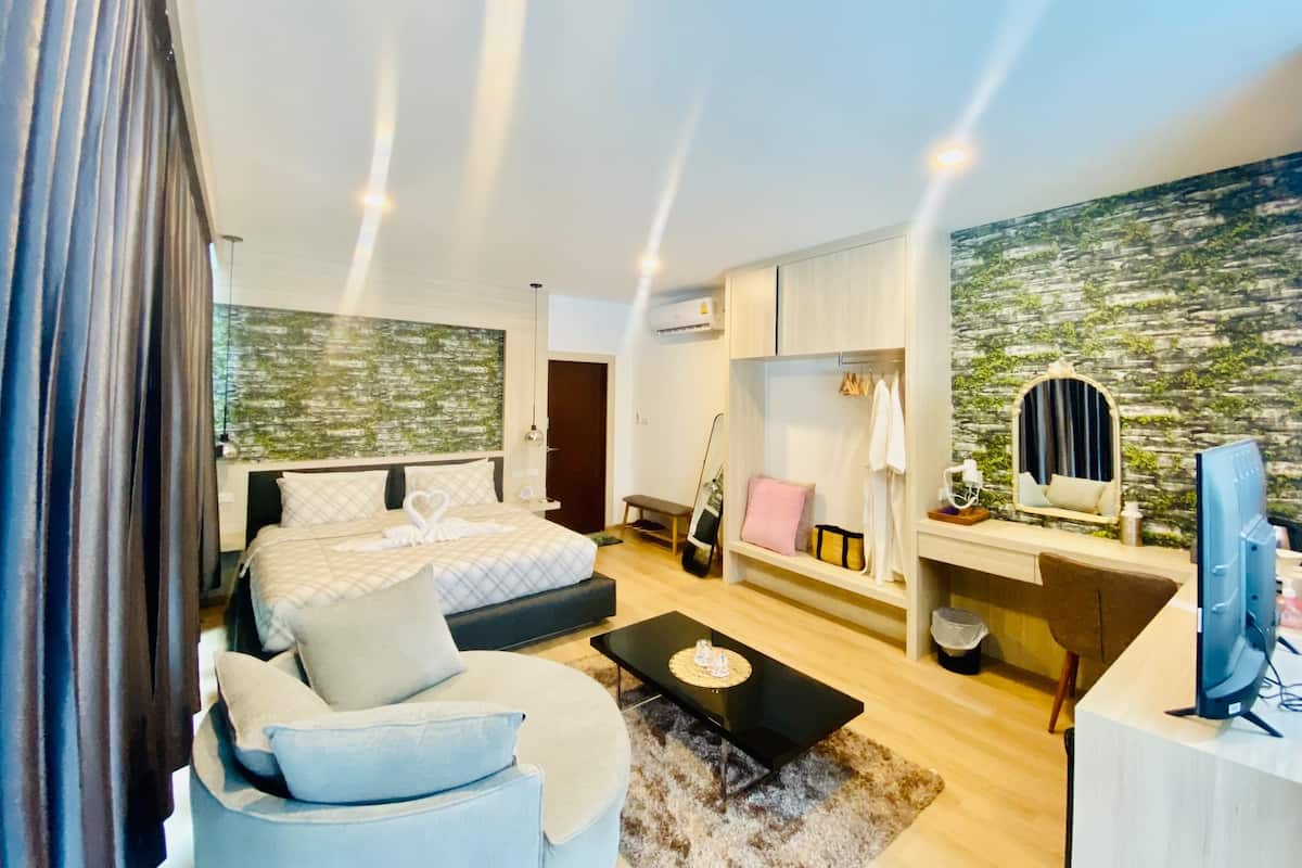 A modern bedroom with a bed, a sofa, a desk, and a television.