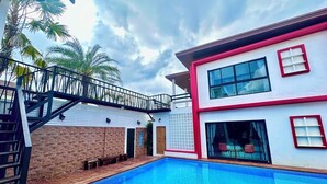 Un edificio moderno di due piani con piscina, terrazza in legno e balcone.