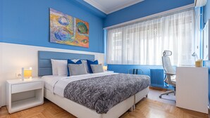 Un dormitorio con cama, mesita de noche, lámpara y escritorio con silla.