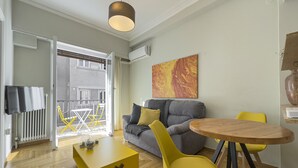 Una sala de estar moderna con un sofá gris, sillas amarillas, una mesa de centro de madera y un ventanal grande.
