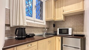 Una cocina con gabinetes color beige, microondas, cafetera y refrigerador.